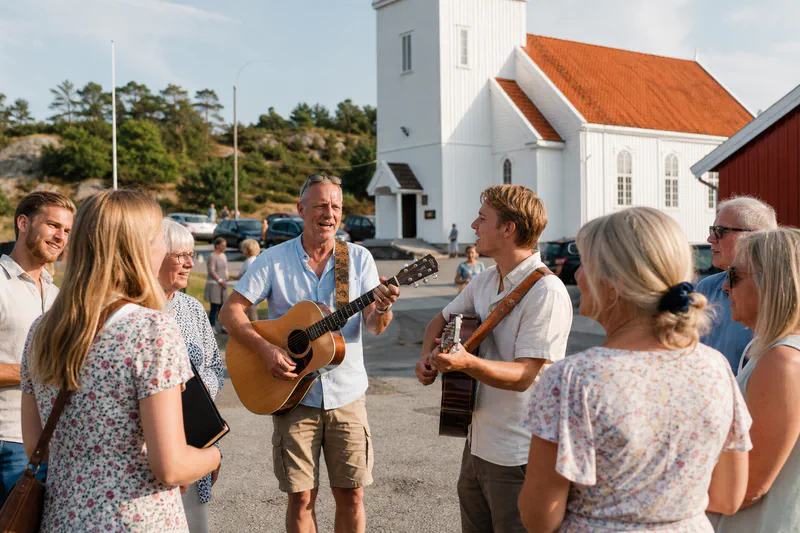 Mennesker som synger sammen utenfor en menighet på en sommerdag.